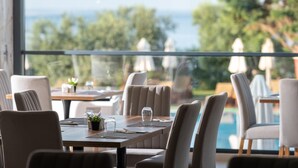 A dining area with a view of the sea, tables with chairs, and umbrellas. - Sea Coast Resort (Polygyros)