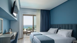 A hotel room with a bed, a desk, a chair, a TV, and a view of the ocean. - Sea Coast Resort (Polygyros)
