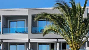 A modern hotel with multiple balconies, a palm tree, and outdoor seating. - Sea Coast Resort (Polygyros)