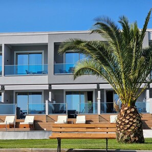A modern hotel with multiple balconies, a palm tree, and outdoor seating. - Sea Coast Resort (Polygyros)
