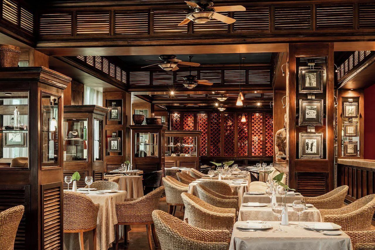 A restaurant with wicker chairs, tables set for dining, and ceiling fans.