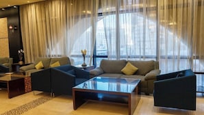 A modern living room with a sofa set, a coffee table, and a view of the city through sheer curtains. - Al Safwa Tower 3 Hotel -EX (Makkah)