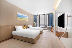 A hotel room with two beds, a desk, a chair, a flat-screen TV, and a large window. - Holiday Inn Riyadh The Business District (Riyadh)