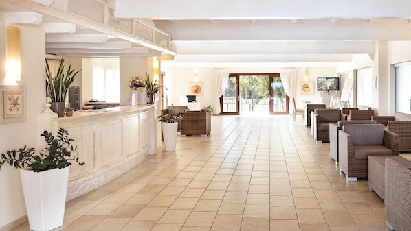 A spacious lobby with a reception desk, seating area, and large windows. - Cala Fiorita (Budoni)