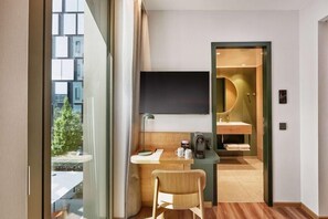 Une chambre d’hôtel moderne équipée d’un bureau, d’une chaise et d’un grand téléviseur.