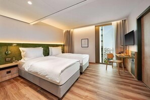 A modern hotel room with two beds, a desk, and a chair. - H+ Hotel Eschborn (Eschborn)