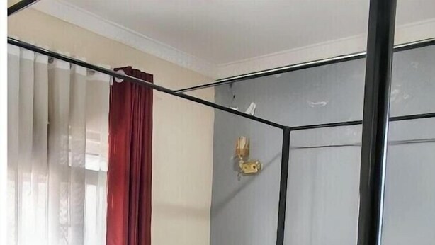 Una cama con dosel con un cabecero rojo, ropa de cama blanca y una mesita de noche de madera al lado.
