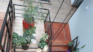 Una escalera de madera con barandillas de metal, plantas en macetas y lámparas colgantes.