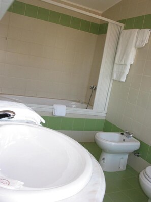 Un baño con una bañera grande, un bidé y un inodoro.