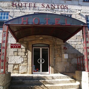 La entrada al Hotel Santos, con fachada de piedra y un acceso cubierto.