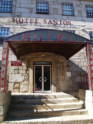 The entrance to Hotel Santos with a stone facade, a covered entrance, and a sign indicating it is a hotel. - Santos Hotel (Guarda)