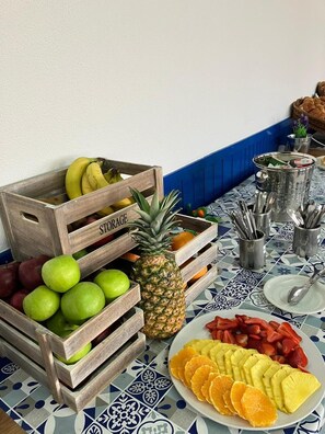 Ein Tisch mit Obstkisten, einer Ananas und einer Schale geschnittenem Obst.