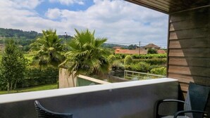 A balcony with two chairs and a small table, overlooking a lush landscape with palm trees and distant hills. - FH Hotel Rural (Felgueiras)