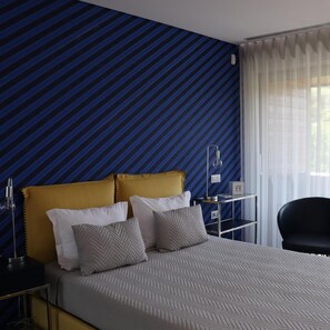 Une chambre d’hôtel avec un lit, une table de chevet, une lampe et une chaise.