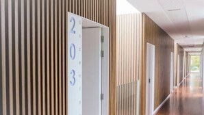 A modern hotel corridor with wooden paneling and a number sign indicating room 203. - FH Hotel Rural (Felgueiras)