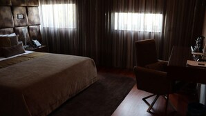 A hotel room with a large bed, a desk, a chair, and a window with curtains. - FH Hotel Rural (Felgueiras)
