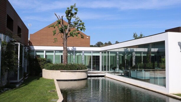 A modern building with a glass facade, a central courtyard with a water feature, and a tree. - FH Hotel Rural (Felgueiras)