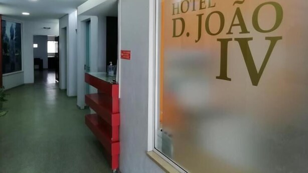 Interior de un hotel con una recepción, una escalera y una pared con el nombre del hotel.