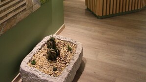 A reception area with a reception desk, a painting of a church, and a small potted plant. - Hotel San Francisco (Leiria)