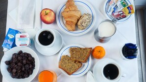 A breakfast tray with croissants, eggs, bacon, toast, fruit, and beverages. - Hotel San Francisco (Leiria)