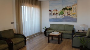 A living room with a green sofa, two armchairs, a coffee table, and a painting of a street scene on the wall. - Hotel San Francisco (Leiria)