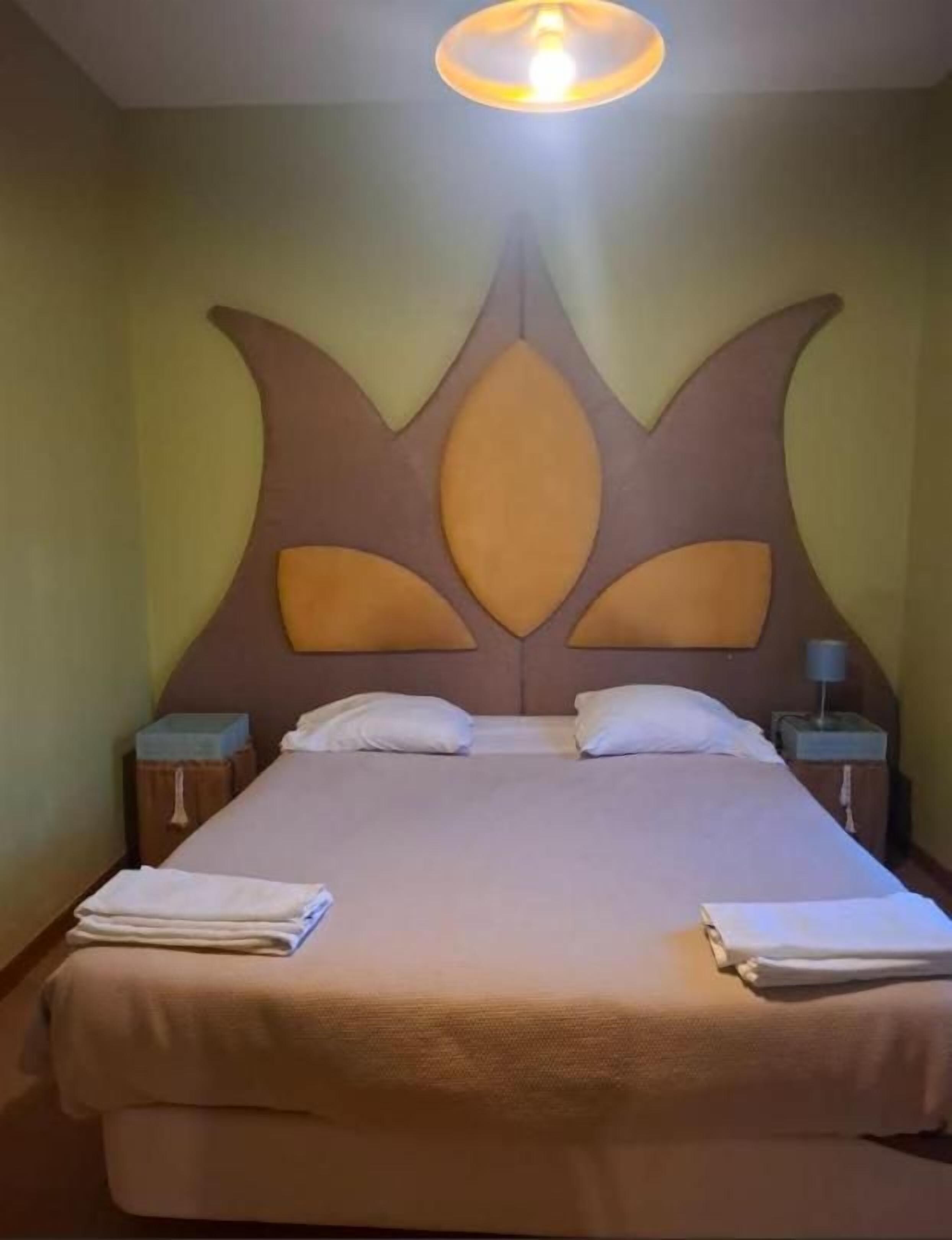 A hotel room with a large bed, two bedside tables, and a unique headboard design.