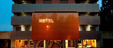 A modern hotel with a prominent 'HOTEL' sign, multiple floors, and a well-lit entrance.