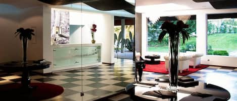 Una sala moderna con piso a cuadros, un separador de vidrio y vista al exterior.