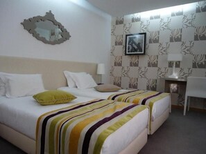 A hotel room with two beds, a desk, and a chair.