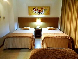 Una habitación de hotel con dos camas, una mesita de noche, una lámpara y un cuadro en la pared.