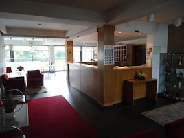 Un hall de hotel con mostrador de recepción, zona de estar y vitrina de vidrio.