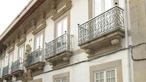 Un immeuble doté de nombreux balcons, de fenêtres blanches et d’une façade en pierre.