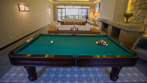 A pool table with balls, a sofa, and a fireplace in a room with patterned flooring and a stone accent wall. - Hotel Brazao (Vila do Conde)