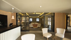 Un hall d’entrée moderne avec un comptoir d’accueil, un espace salon et des cloisons en verre.