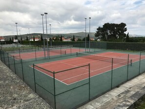 An outdoor tennis court with a green fence, surrounded by a hedge and trees. - Penedono Medieval Hotel (Penedono)