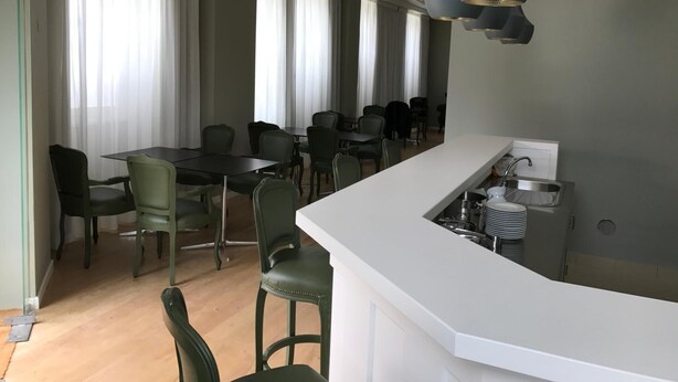 A modern kitchen with a white countertop, a sink, and a dining area with chairs and a table. - Penedono Medieval Hotel (Penedono)
