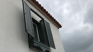 A building with a white facade, a red-tiled roof, and a window with black shutters. - Penedono Medieval Hotel (Penedono)