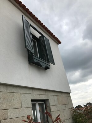 A building with a white facade, a red-tiled roof, and a window with black shutters. - Penedono Medieval Hotel (Penedono)