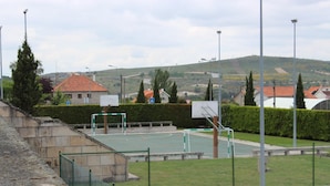An outdoor basketball court with a net, surrounded by a low fence and a hedge. - Penedono Medieval Hotel (Penedono)