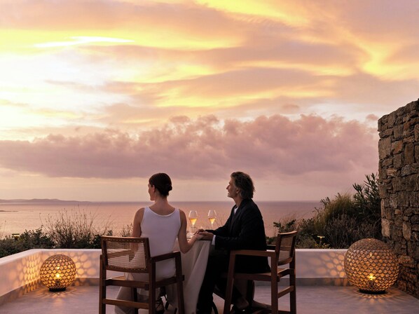 Two people seated at a table with a view of the sea and sunset. - Deos Mykonos (Mykonos)