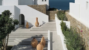 A white building with a view of the sea, steps leading to a door, and three large vases on the ground. - Deos Mykonos (Mykonos)