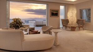 A modern living room with a large window, a sofa, two armchairs, a coffee table, and a painting on the wall. - Deos Mykonos (Mykonos)