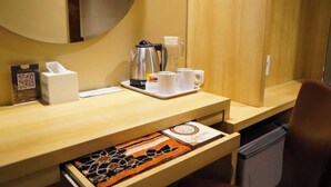 A hotel room with a wooden desk, a coffee maker, cups, a tissue box, and a framed picture. - Syariah Hotel Sentul (Bogor)