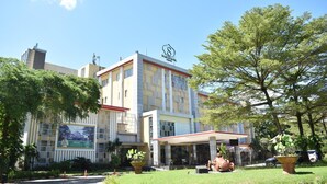 A hotel with a central entrance, a covered outdoor area, and a large garden with a statue. - Syariah Hotel Sentul (Bogor)