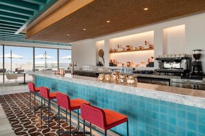 A bar area with a pool view, bar stools, and a coffee machine. - Abesq Doha Hotel & Residences (Doha)