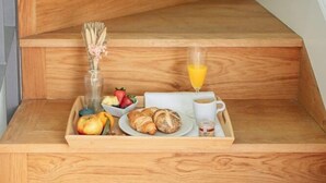 A wooden staircase with a tray of breakfast items including fruits, croissants, and a glass of orange juice. - Palacio de la Corredera (Jerez de la Frontera)