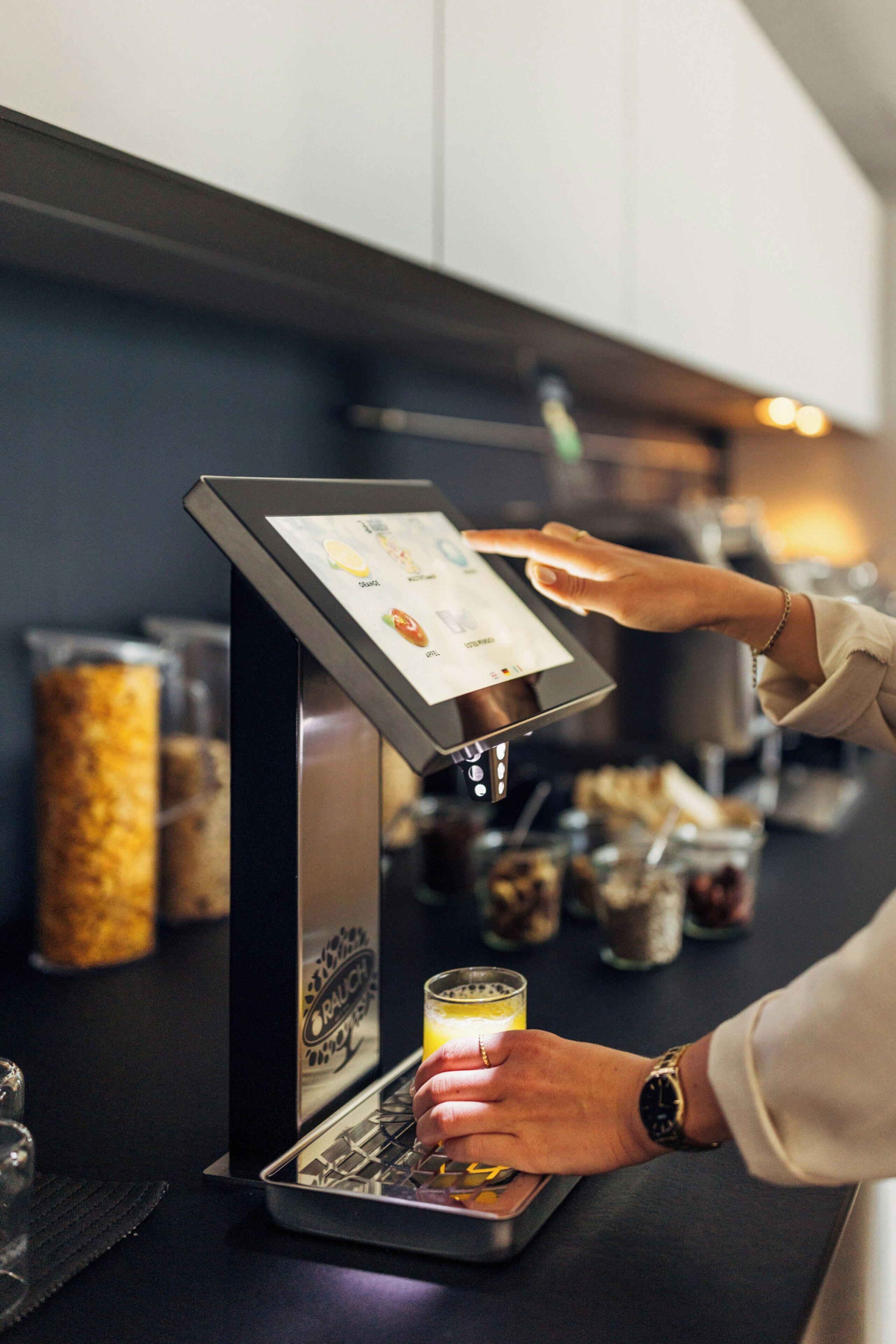 A person using a touchscreen coffee machine with a menu display.