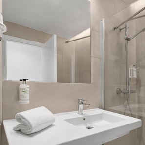 A modern bathroom with a white sink, a glass shower enclosure, a mirror, and a bottle of hand soap. - B&B Hotel Finestrat (Finestrat)