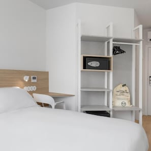 A hotel room with a bed, a desk, a wardrobe, and a bag of toiletries. - B&B Hotel Finestrat (Finestrat)