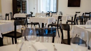 A restaurant with multiple tables set for dining, each with chairs and wine glasses. - Pm Hotel (Catanzaro)